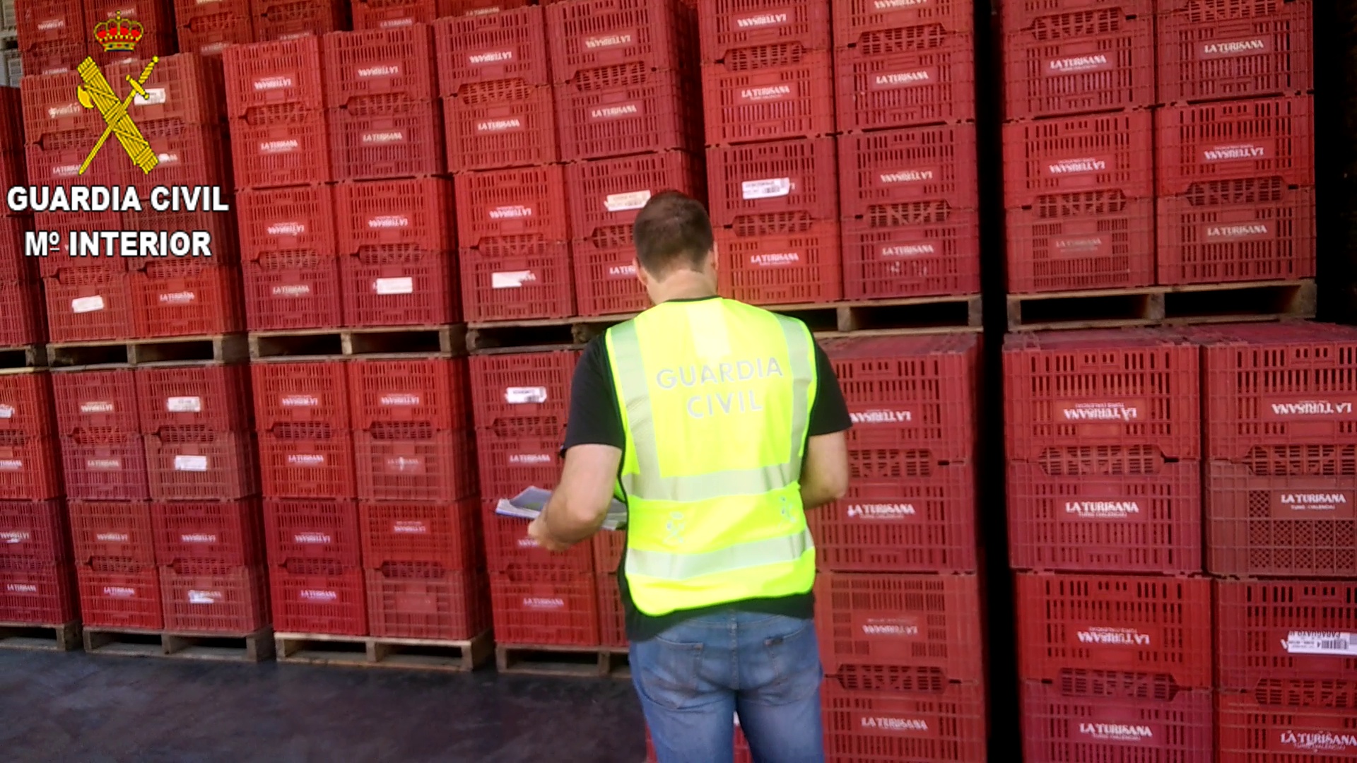 Un agente ante los cajones para transporte de frutas.